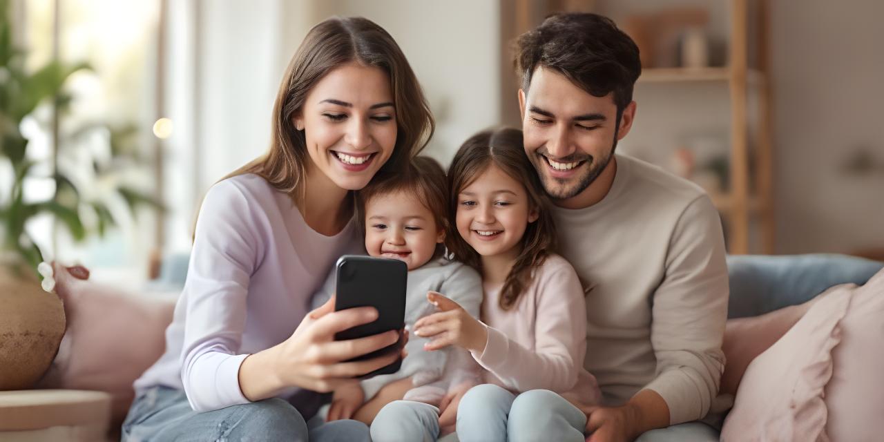 A family of four smiling while viewing their location tracking app on a smartphone in a bright living room